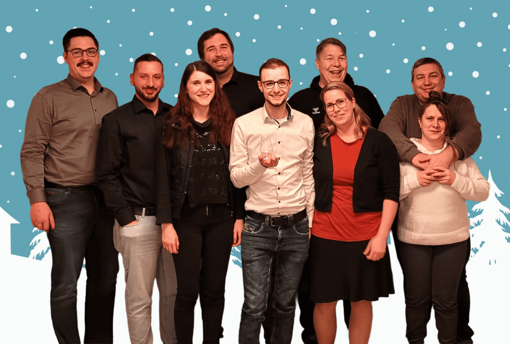 Das Team der Konzept3 IT mit Partnern vor winterlichem Hintergrund auf der Weihnachtsfeier.