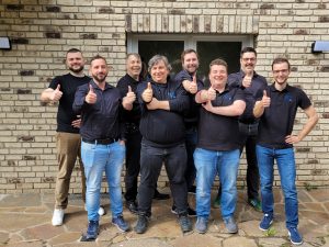 Das Team von KONZEPT3 IT, zusammenstehend mit freundlichem Blick und Daumen hoch.