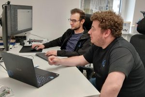 Zwei Mitarbeiter von Konzept3 IT beim internen Wissenstransfer am Arbeitsplatz.